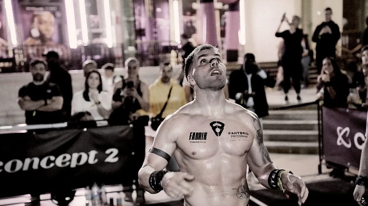 Atleta de Fabrik tras cruzar la meta en HYROX París, con el logo de FAHYBRID Program en el pecho, mirando al cielo